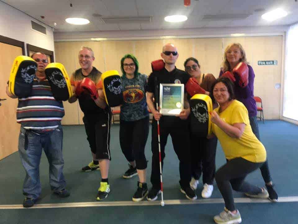 7 People during trial of Martial Arts Style Fitness class holding boxing gloves and pads