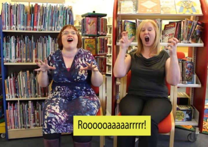 Two ladies reading and translating BSL story books. Caption reads "Roar"