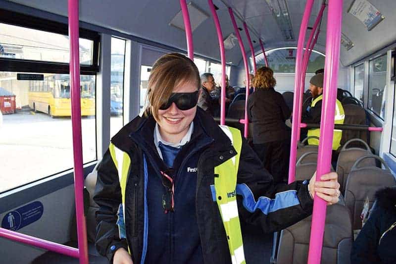 Girl on bus with blacked out glasses.