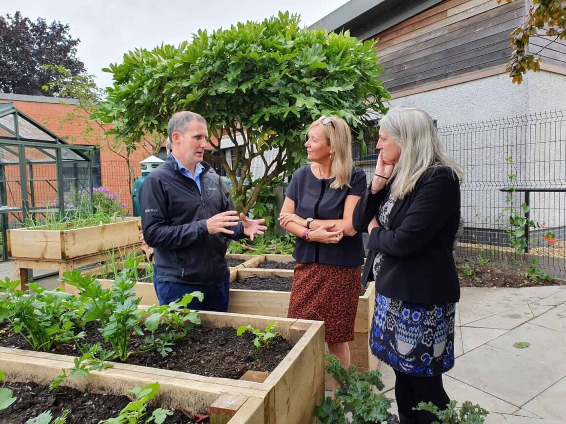 Three people standing in front of a planter having an in depth discussion
