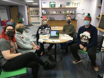 Linsey, Jill, Peter A, Colin and Martin in the tech hub. They are wearing festive deely boppers and christmas jumpers. Everyone is wearing a mask.