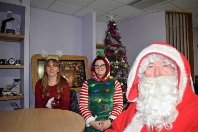 Laura with Linsey elf and santa, there is a christmas tree behind them and an image of a crackling fire on the tiny tablet