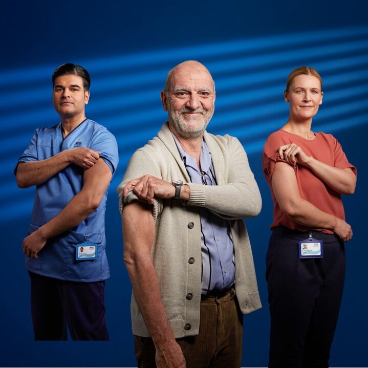 Three people in medical scrubs rolling sleeves up to show where they had injections