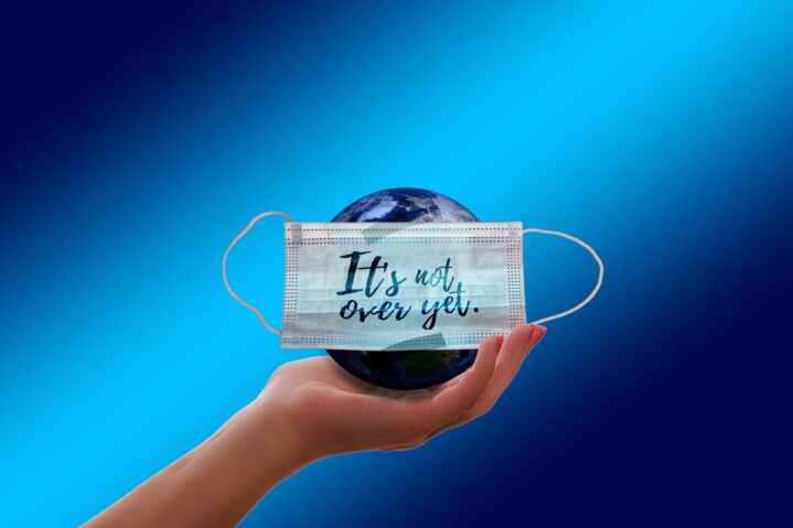 Globe in a mask with the legend "it's not over yet" written on it