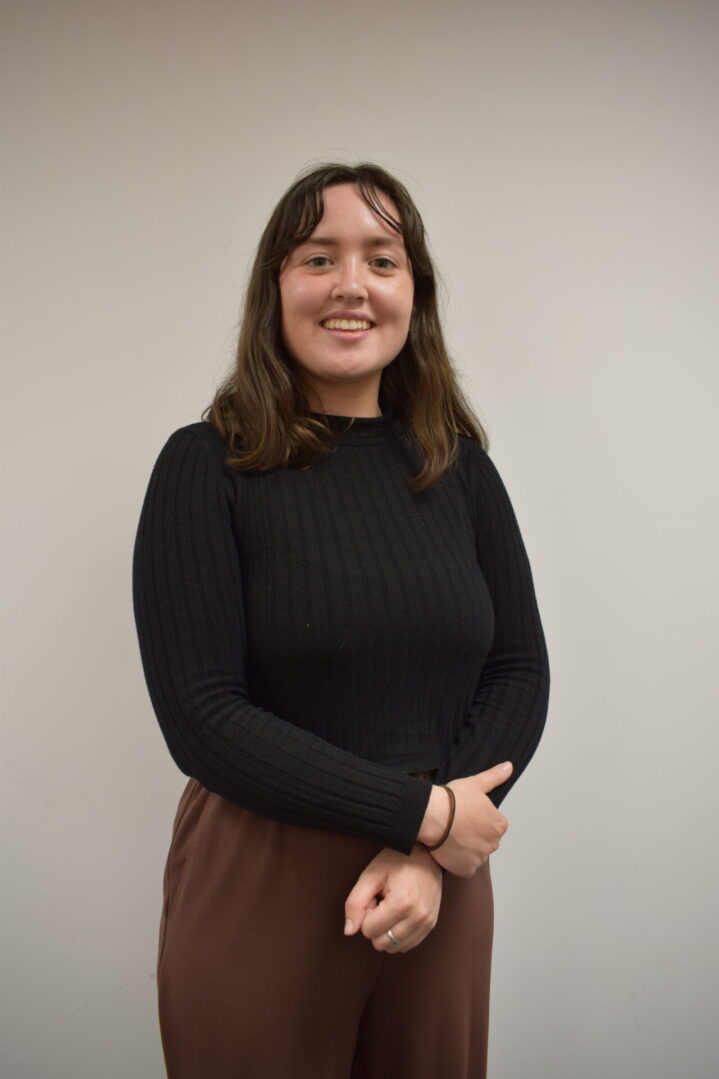 Sara Burns in black jumper hands folded in front