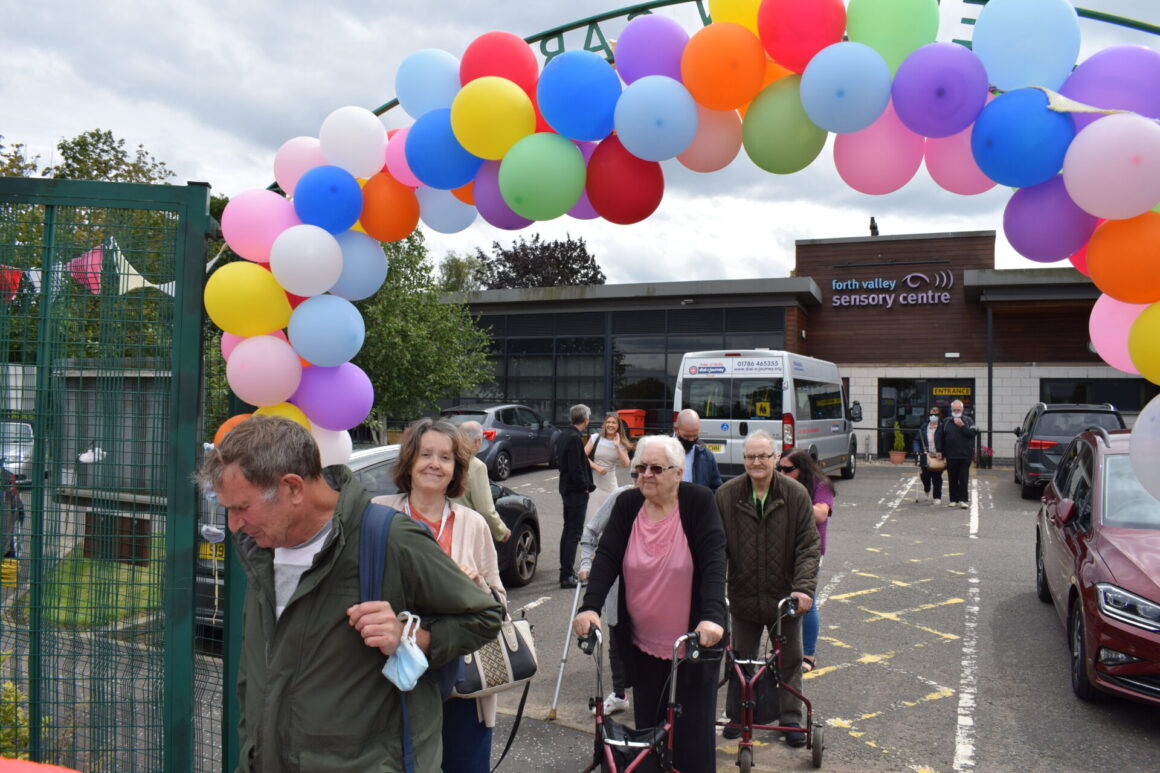 Lines of people coming into garden through balloon arch