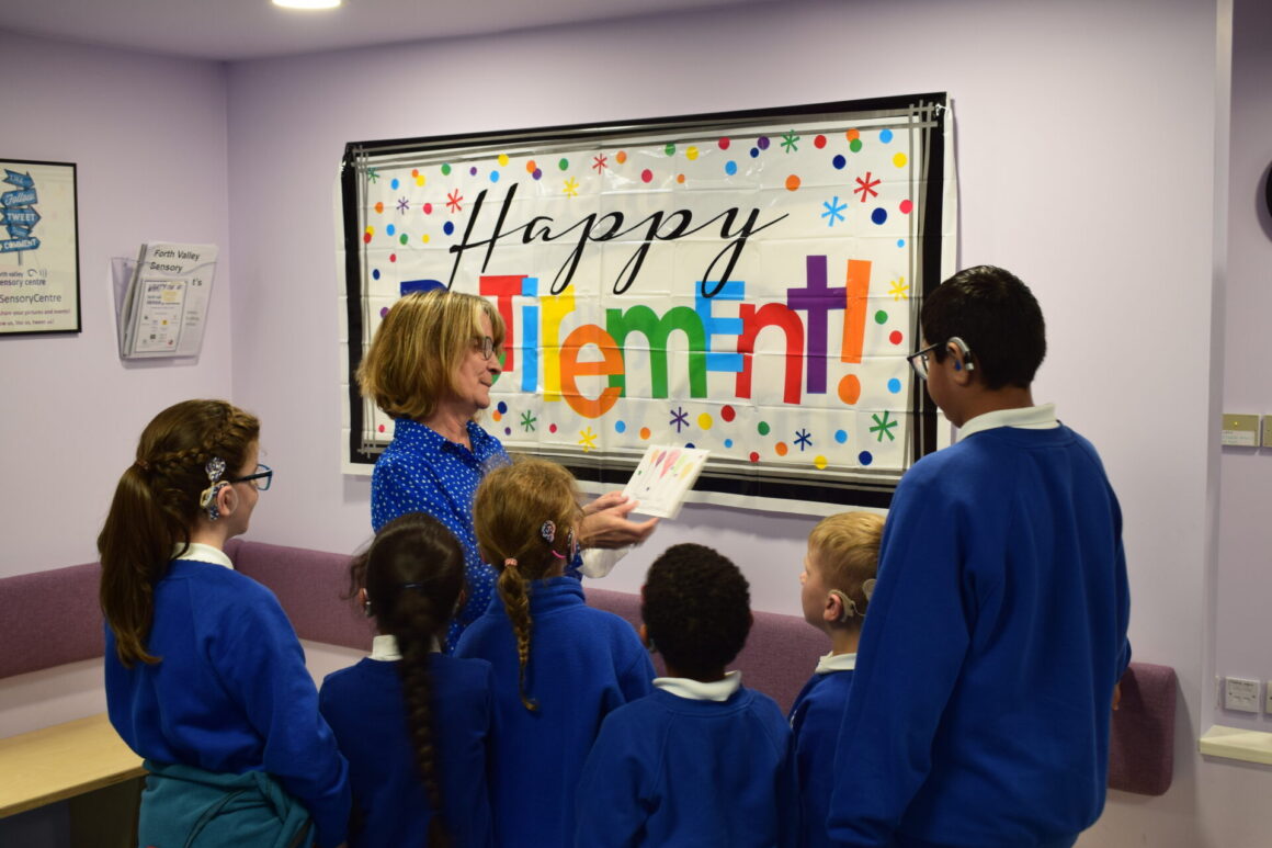 Caroline reading her cards from Windsor Park with pupils gathered around