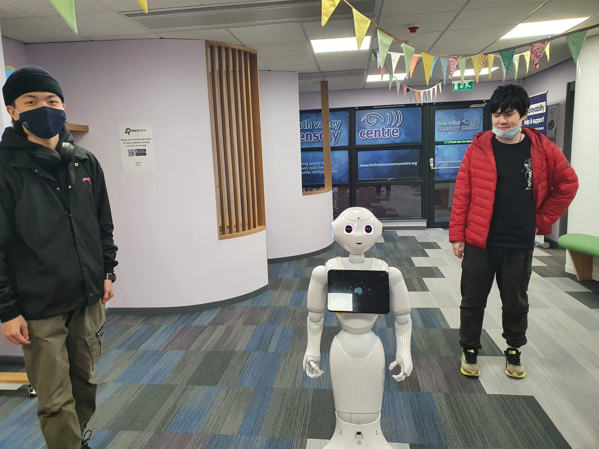The two students developing Pepper stood with him in the Tech Hub