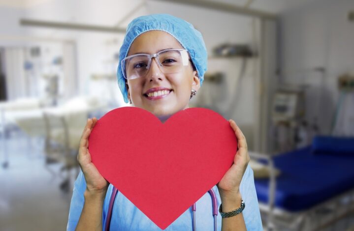 Nurse holding a paper heart with ward in background