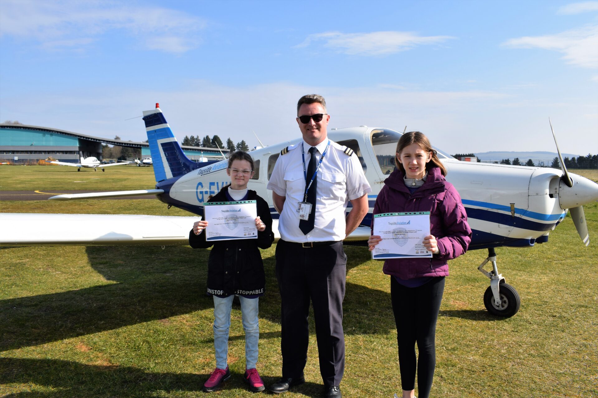 Getting their certificates with pilot Andrew in front of the plane