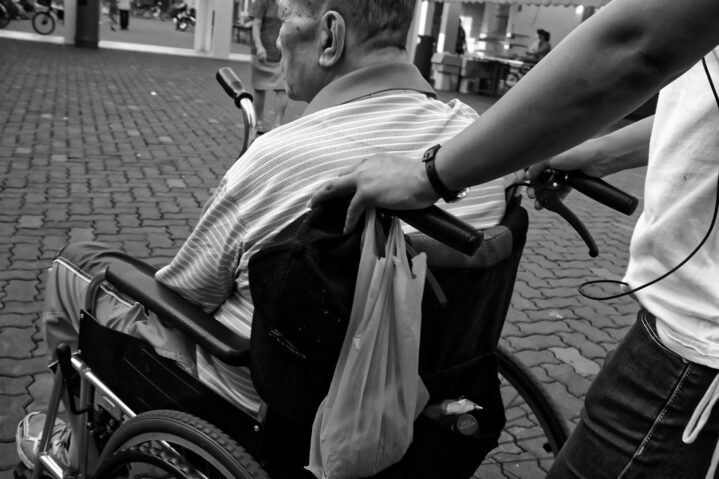 black and white image of a man being pushed in a wheelchair