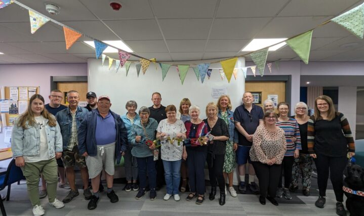A group photo of lots of volunteers smiling and holding a banner that says 'volunteer'.