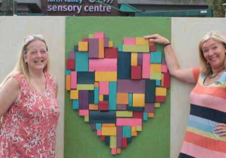 Jacquie and Val standing next to our new Tactile Heart in Sensory garden.