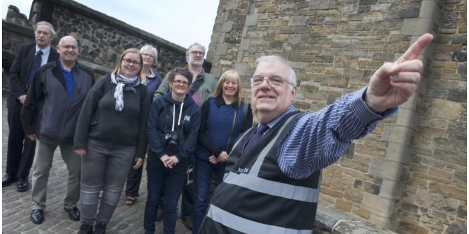 BSL tours of Edinburgh Castle with guide pointing and people in background