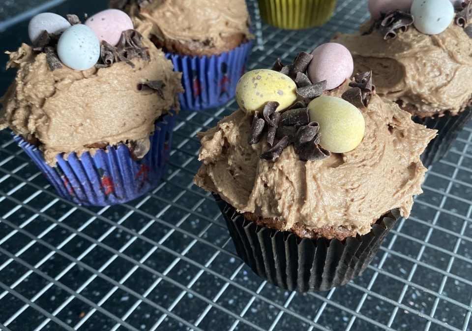 six cupcakes with chocolate icing and mini eggs on top