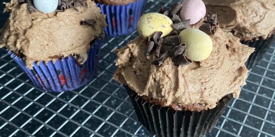 six cupcakes with chocolate icing and mini eggs on top