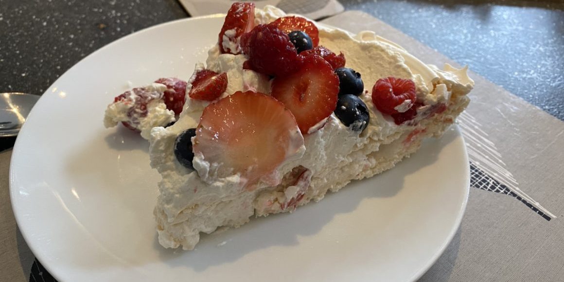 a slice of meringue with cream and fruit on top