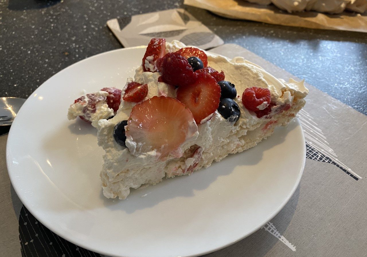 a slice of meringue with cream and fruit on top